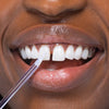 Femme aux dents blanches avec le stick de blanchiment Glow Stick de Diamond Smile sur la dent