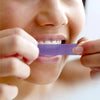 Blanchiment des dents avec les bandes de blanchiment violettes de Diamond Smile sur les dents d'une femme