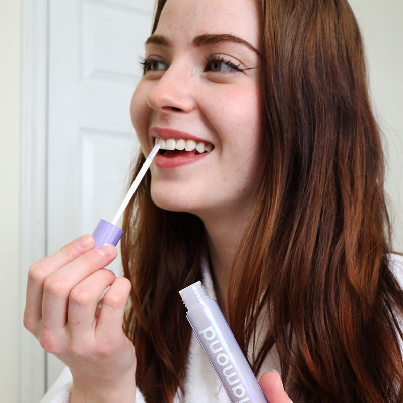 Femme dans la salle de bain avec le stick de blanchiment Diamond Smile dans la main